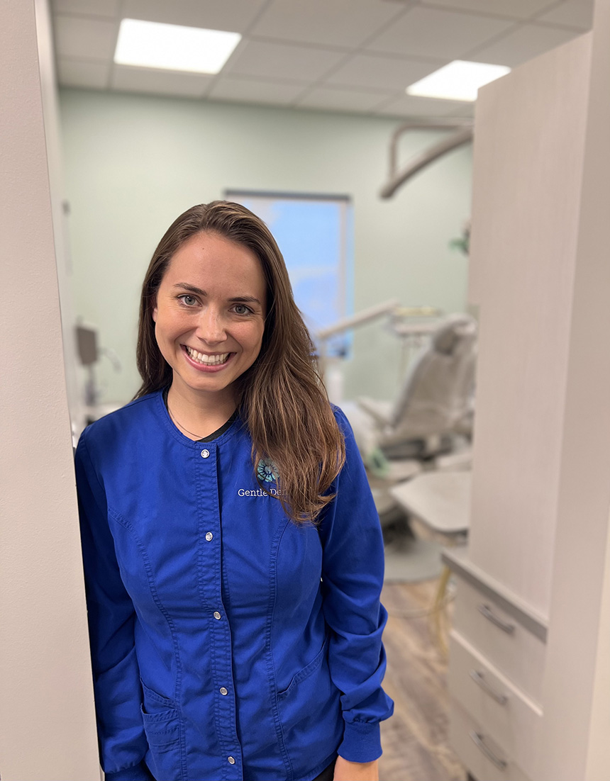 A woman standing in front of a dental office with a smile.