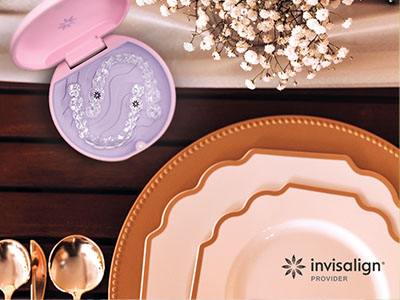 The image shows a collection of tableware items including plates, cups, and other dining accessories arranged on a wooden surface with a pink makeup compact in the foreground.