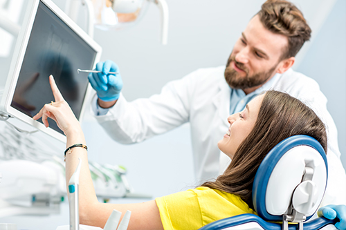 A man in a lab coat stands next to a woman wearing a headset, both engaged with a medical monitor.